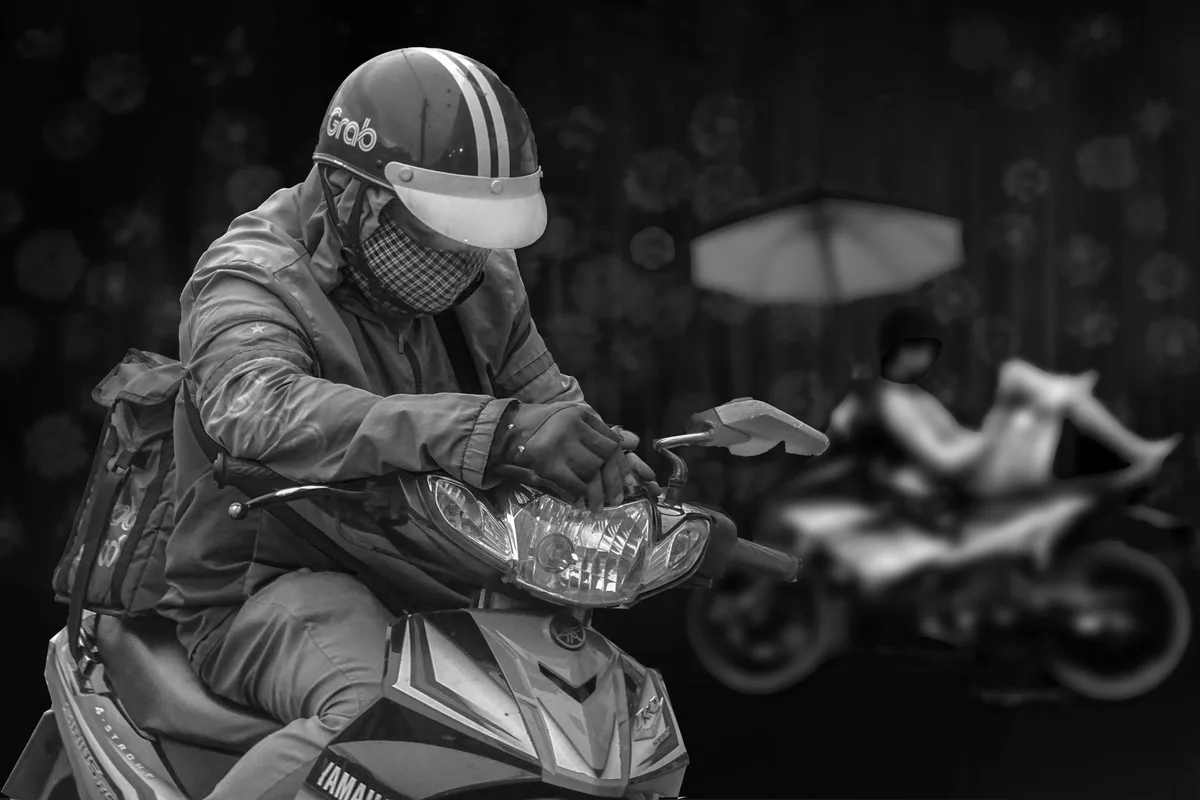 A masked delivery rider on a motorcycle, geared up for last-mile parcel delivery, the method most COD orders in Malaysia rely on